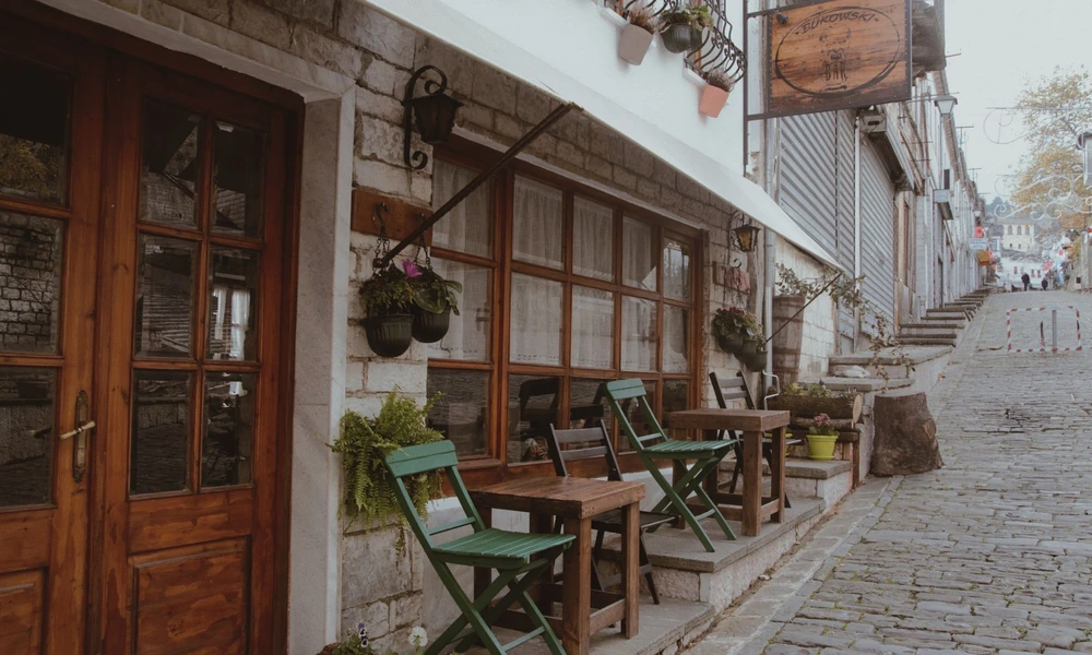 Brukowana uliczka Starego Bazaru w Gjirokastrze ze stolikami kawiarni na zewnątrz